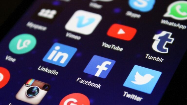 Close-up of a smartphone screen showing various social media app icons such as Facebook and Twitter.